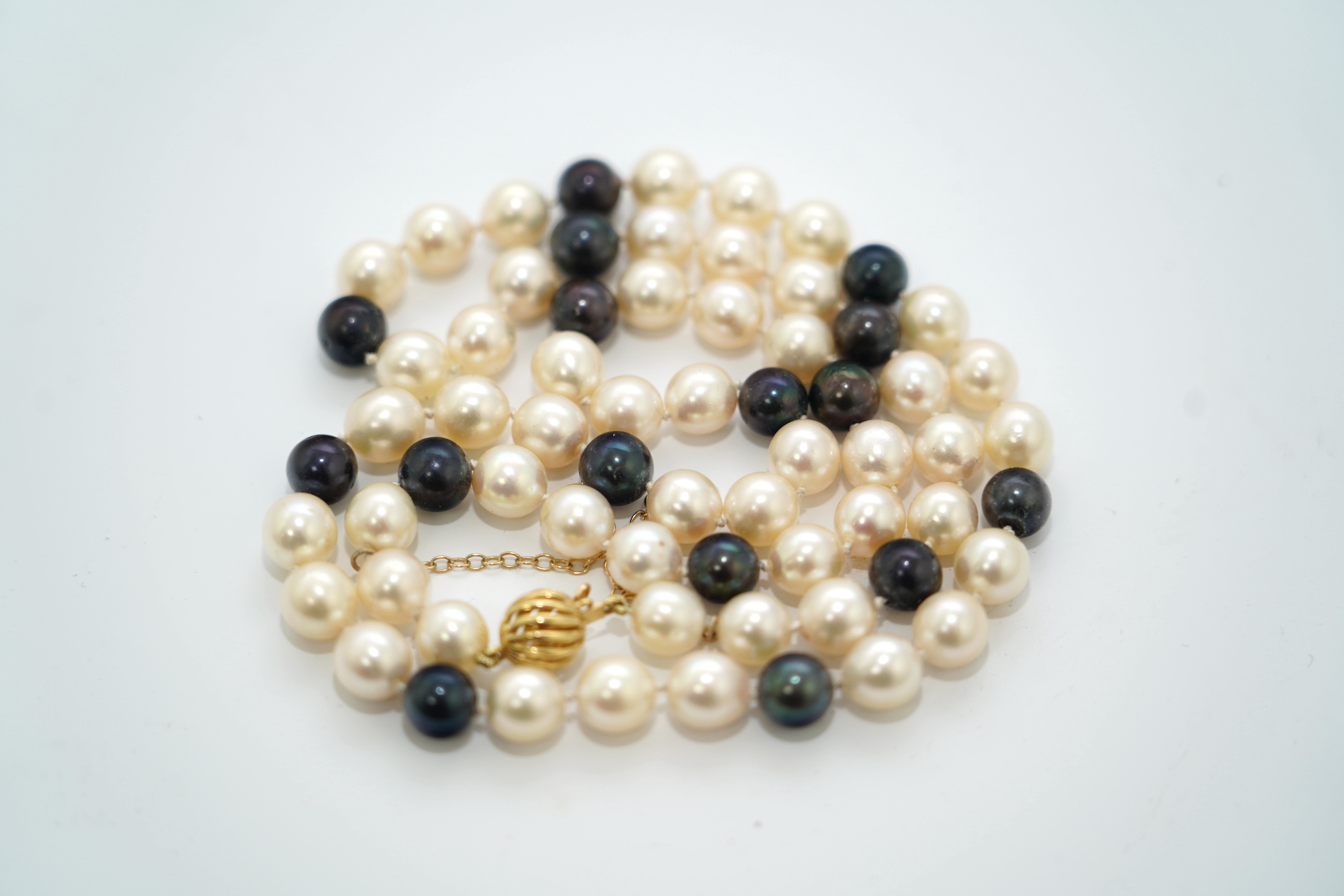 A modern single strand two colour cultured pearl necklace, with 750 yellow metal clasp, 58cm. Condition - fair